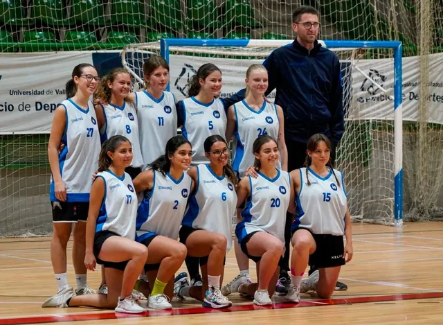 Basketball team and coach posing together on an indoor court.