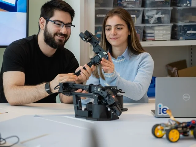Two people working with a robotic arm at a laboratory table.