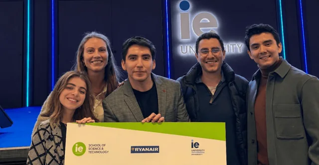 Five people posing with an IE University and Ryanair event board.