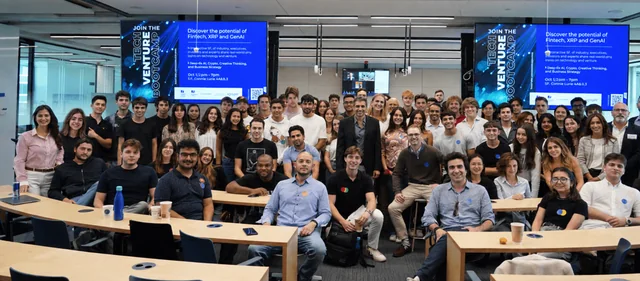 Group photo in a classroom beneath Tech Venture Bootcamp displays.